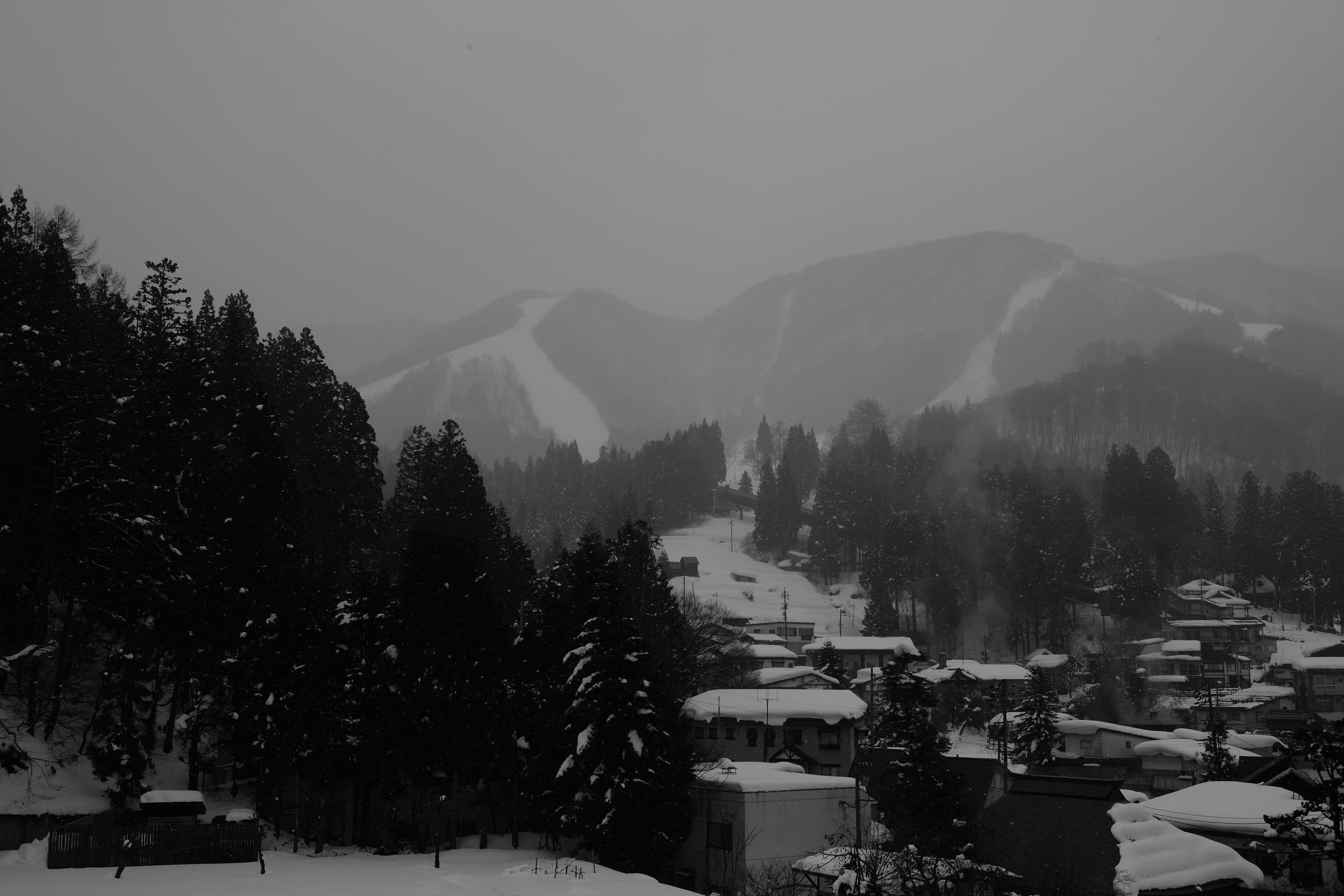 Snowy rooftops of northern Nozawa Onsen village with Mount Kenashi behind